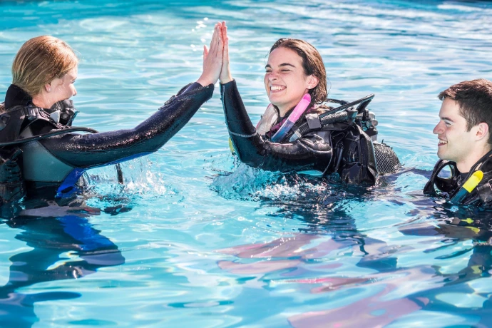 Cursist en instructeur geven elkaar een high five in het zwembad