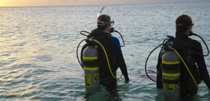 Duiker stapt vanaf de kust het water in voor een buitenwaterduik met Nitrox