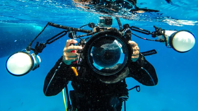 Duikinstructeur onder water met een camera, klaar om les te geven volgens het PADI-systeem