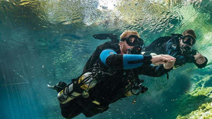 Duiker in sidemount-configuratie oefent zijn trim in helder blauw water