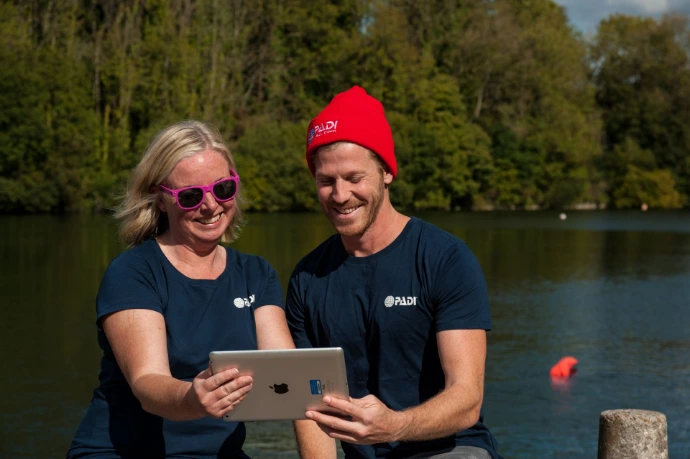 Instructeur en kandidaat bespreken samen de planning op een tablet aan de waterkant tijdens een Pro-opleiding